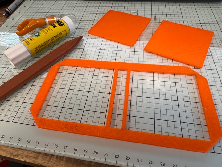 A glass cutting mat has several papercraft tools on top of it.